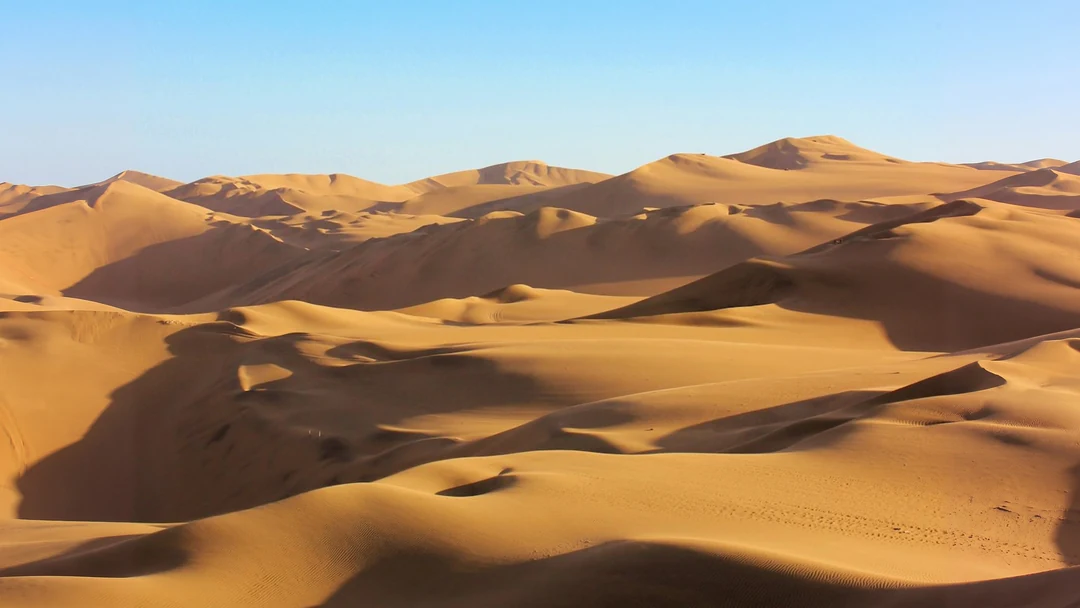Wide 16:9 banner of golden dunes and pale sky, the same desert photo after the image expander
